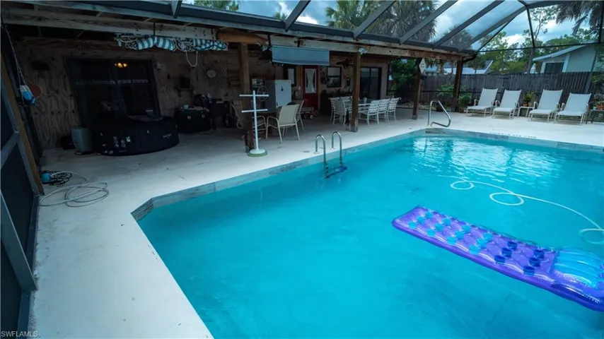 View of swimming pool featuring glass enclosure and a patio area