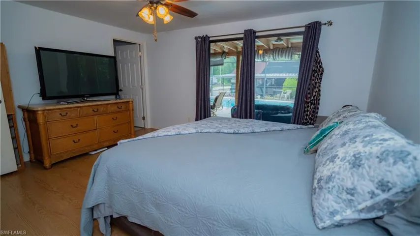 Bedroom with wood-type flooring, ceiling fan, and access to exterior