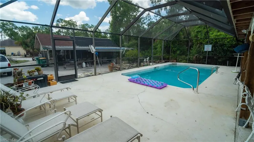 View of pool featuring a patio area and screen enclosure