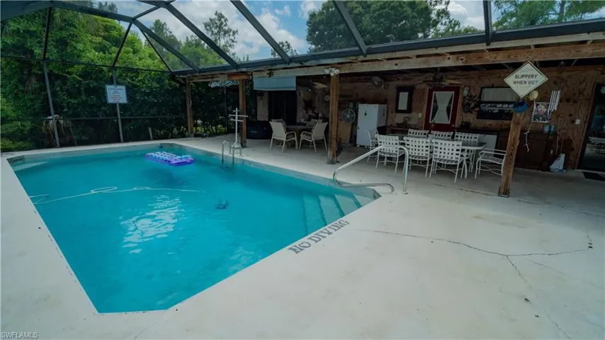View of swimming pool with a patio area and glass enclosure
