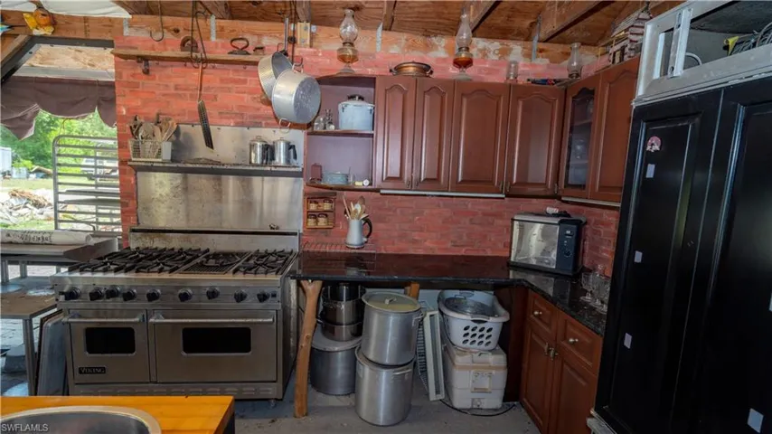 Kitchen featuring black refrigerator, double oven range, and dark stone countertops