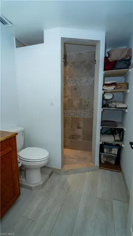 Bathroom with a tile shower, toilet, and vanity
