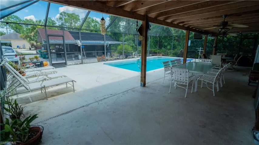 View of pool featuring a patio, glass enclosure, and ceiling fan