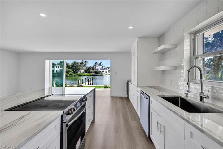 Chefs kitchen overlooks living and dining areas.  Kitchen features custom soft close cabinets, Waterfall counters on the island, cook top range and separate convection/ microwave oven, wine fridge, large picture windows, floor to ceiling bay-front sliders and softly lit with abundant canister lighting.