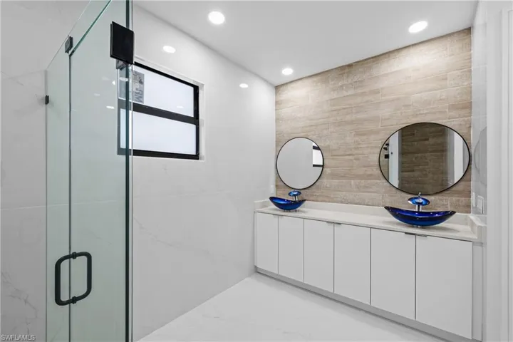 Bathroom with vanity, a shower with shower door, and tile walls