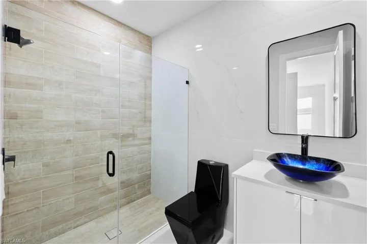 Bathroom featuring vanity, walk in shower, and tile walls