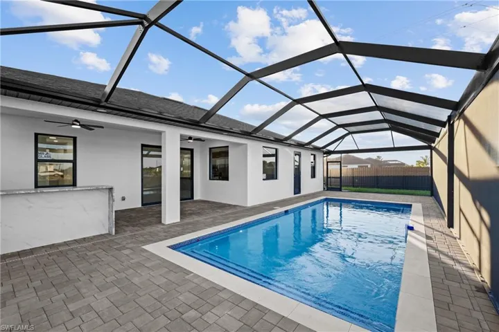 View of swimming pool featuring glass enclosure, ceiling fan, and a patio area