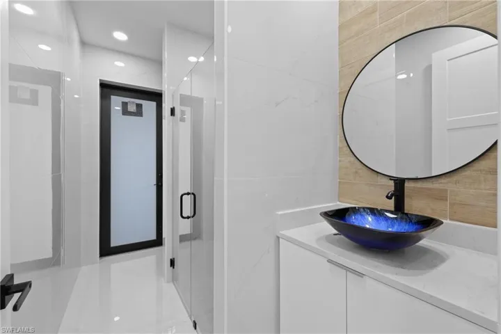 Bathroom featuring vanity, basketball court, a shower with shower door, and tile walls