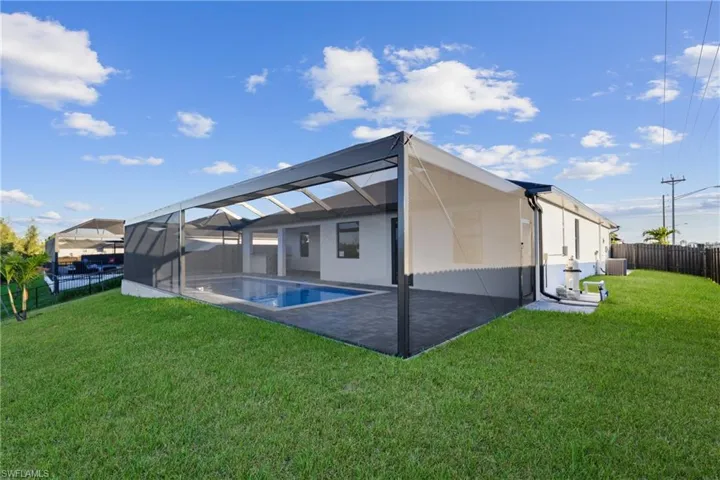 Rear view of property with a yard, a fenced in pool, glass enclosure, and a patio area