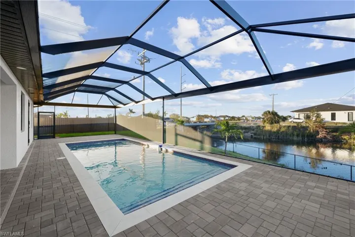 View of pool with a patio, a water view, and a lanai