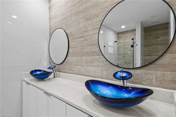 Bathroom with tasteful backsplash, vanity, a shower with shower door, and tile walls