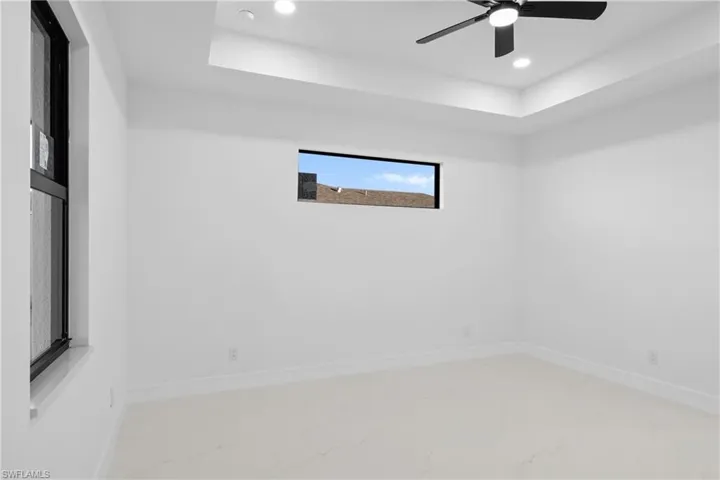 Unfurnished room with ceiling fan and a tray ceiling