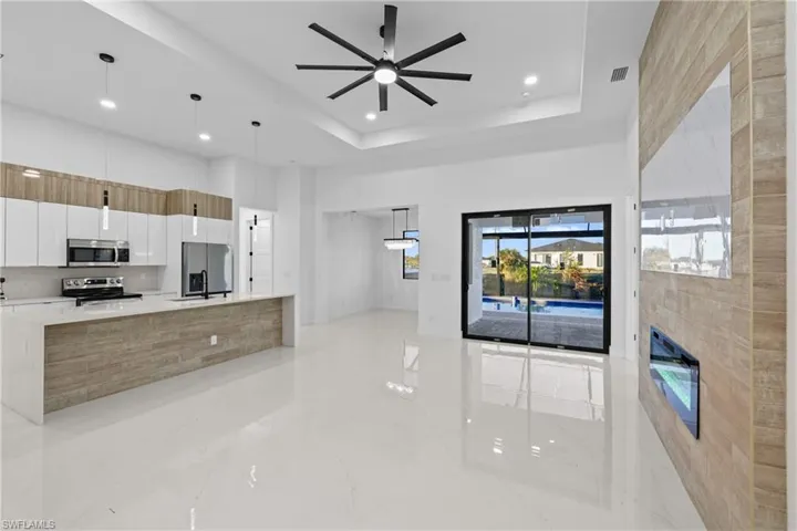 Kitchen featuring white cabinets, hanging light fixtures, ceiling fan, a tray ceiling, and stainless steel appliances
