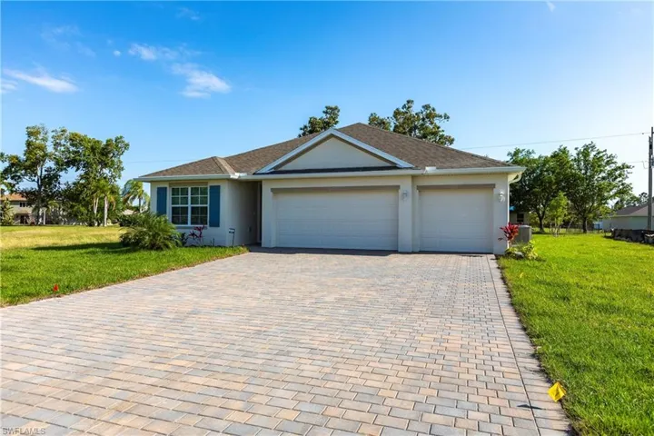 Ranch-style house featuring a garage and a front lawn