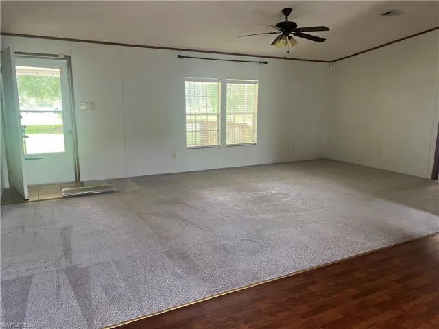 Empty room featuring ceiling fan, crown molding, and wood finished floors