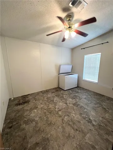 Empty room featuring a textured ceiling and ceiling fan
