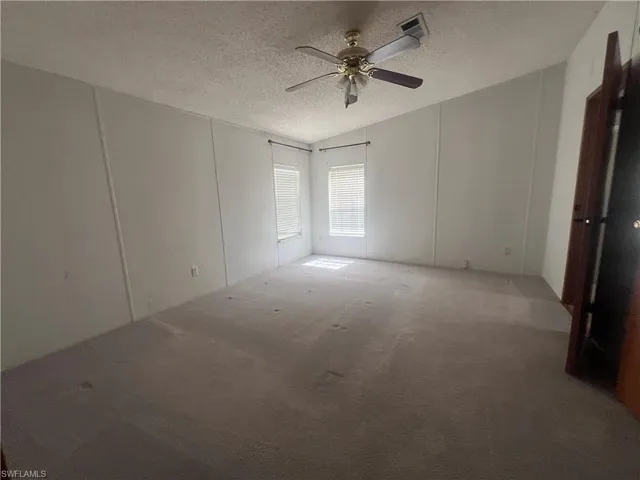 Spare room featuring a textured ceiling, ceiling fan, carpet, and vaulted ceiling