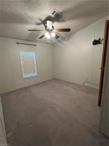 Carpeted spare room featuring a textured ceiling and a ceiling fan