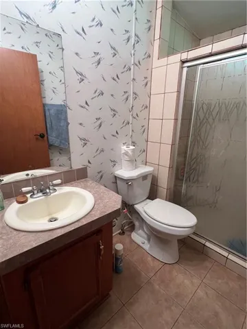 Bathroom with a shower stall, vanity, tile patterned flooring, and tile walls
