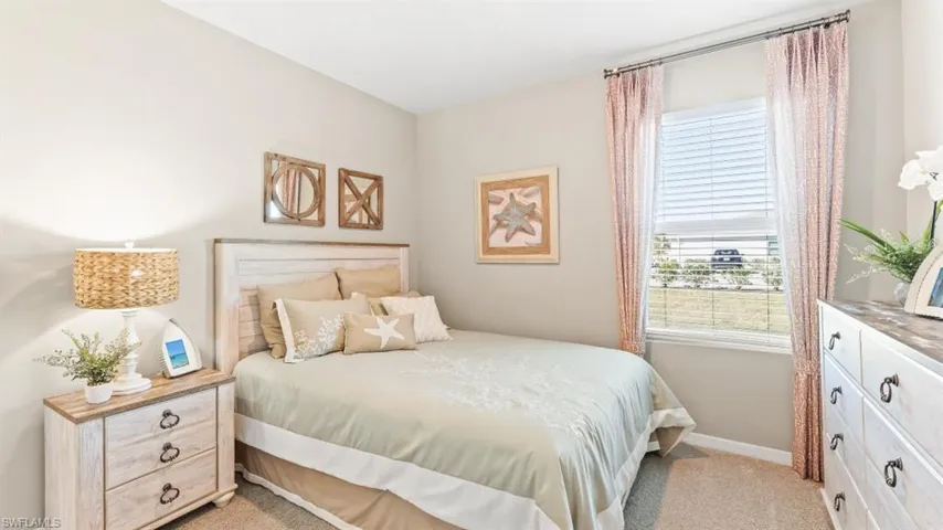 Model Home. This bedroom features a window with blinds and curtains, a light-colored headboard, and carpeting