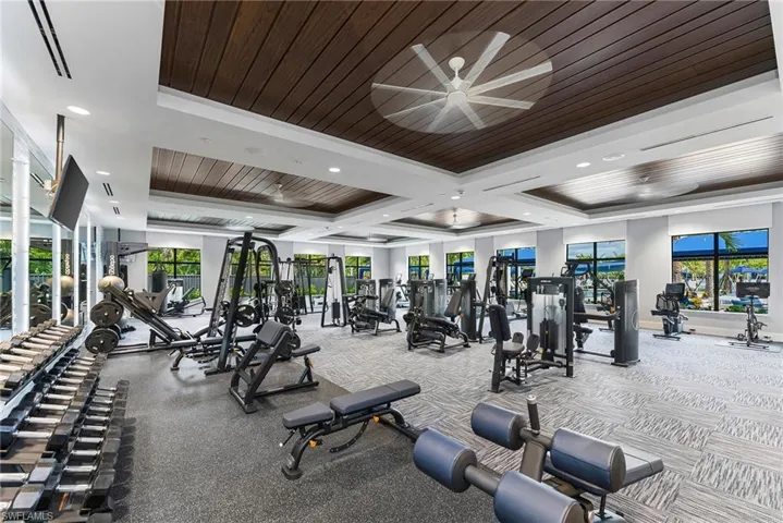 Exercise room with ceiling fan, wood ceiling, a raised ceiling, and ornamental molding