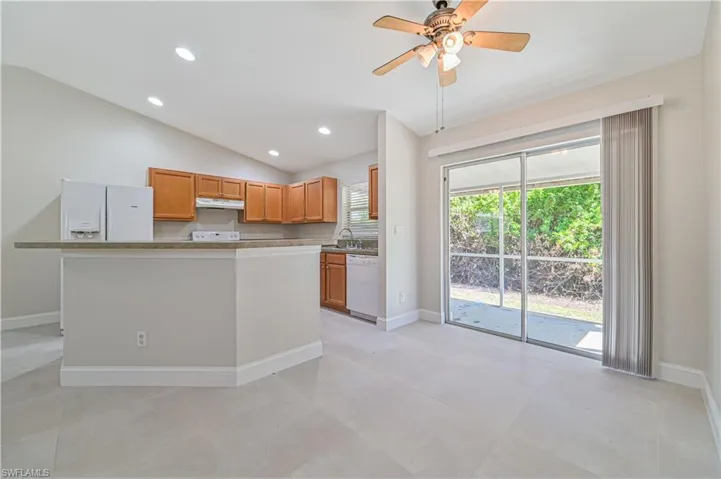Kitchen with lofted ceiling, white appliances, sink, ceiling fan, and light tile floors