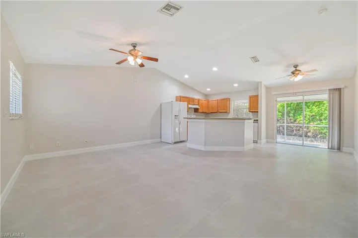 Unfurnished living room featuring lofted ceiling, light tile flooring, and ceiling fan