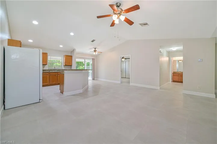 Unfurnished living room with sink, lofted ceiling, light tile flooring, and ceiling fan