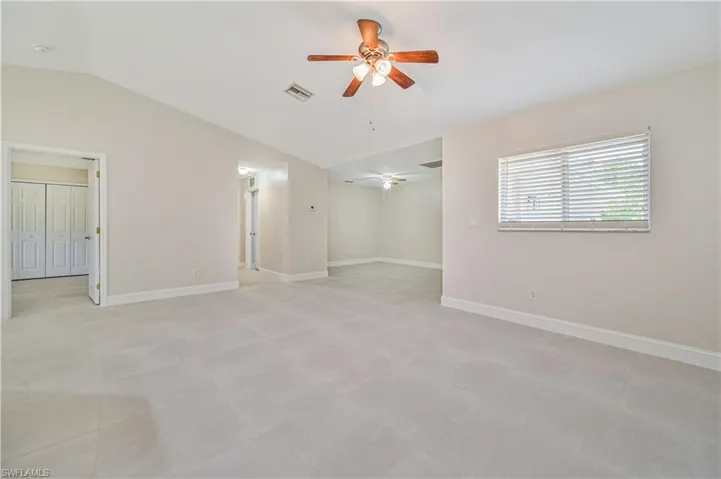 Tiled empty room with ceiling fan and lofted ceiling