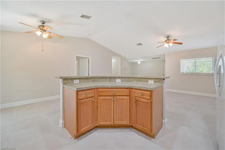 Kitchen featuring lofted ceiling, ceiling fan, light tile floors, and a kitchen island
