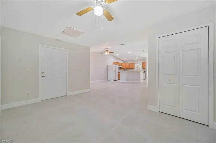 Unfurnished living room featuring ceiling fan, vaulted ceiling, and light tile floors