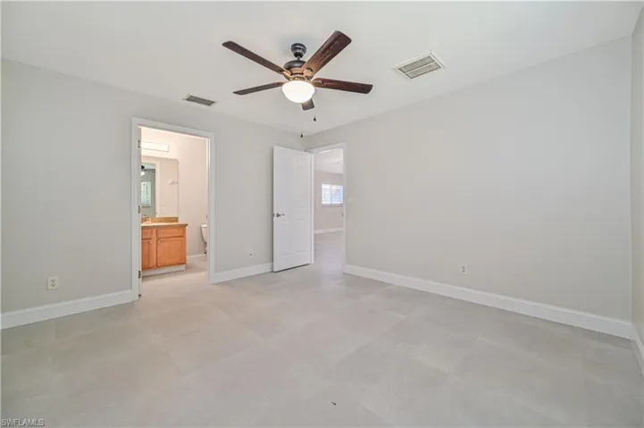 Unfurnished bedroom featuring connected bathroom, ceiling fan, and light tile floors