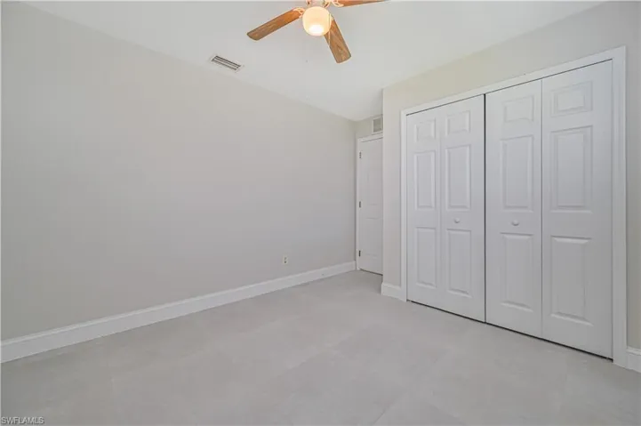 Unfurnished bedroom with ceiling fan, a closet, and light tile flooring