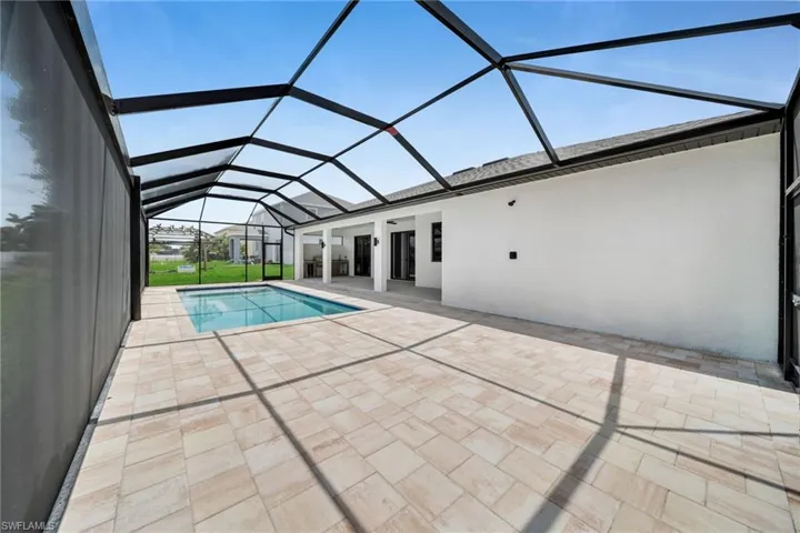Outdoor pool featuring glass enclosure and a patio area
