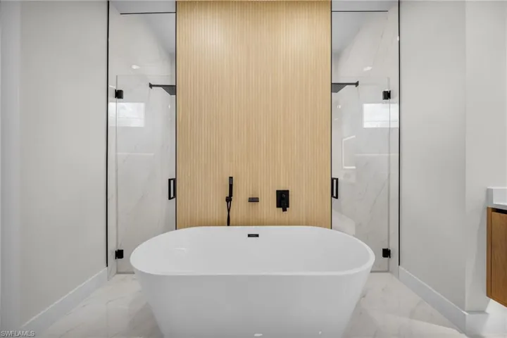 Full bathroom with a freestanding tub, baseboards, and marble finish floor