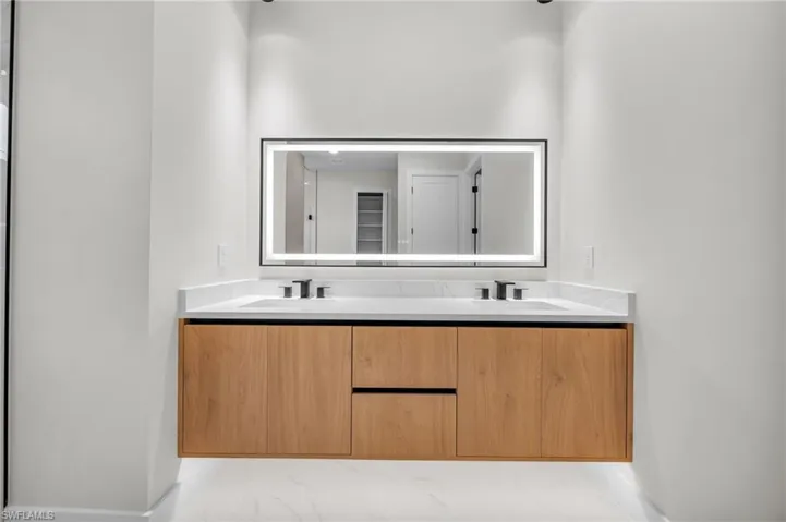 Bathroom with a sink, baseboards, double vanity, and marble finish floor