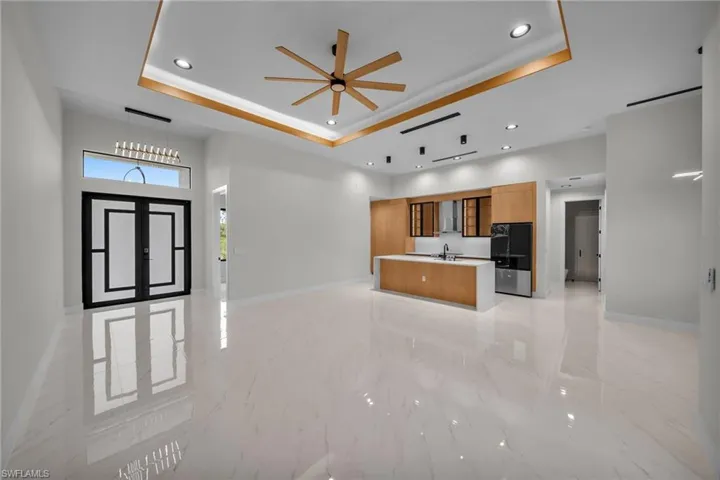 Unfurnished living room featuring recessed lighting, baseboards, a raised ceiling, and marble finish floor
