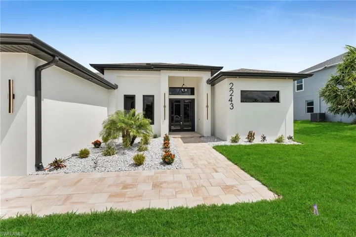 View of front of house featuring central AC, a front lawn, and stucco siding