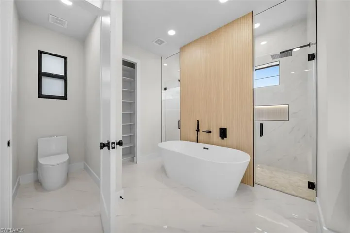 Full bathroom with visible vents, marble finish floor, toilet, a soaking tub, and a marble finish shower