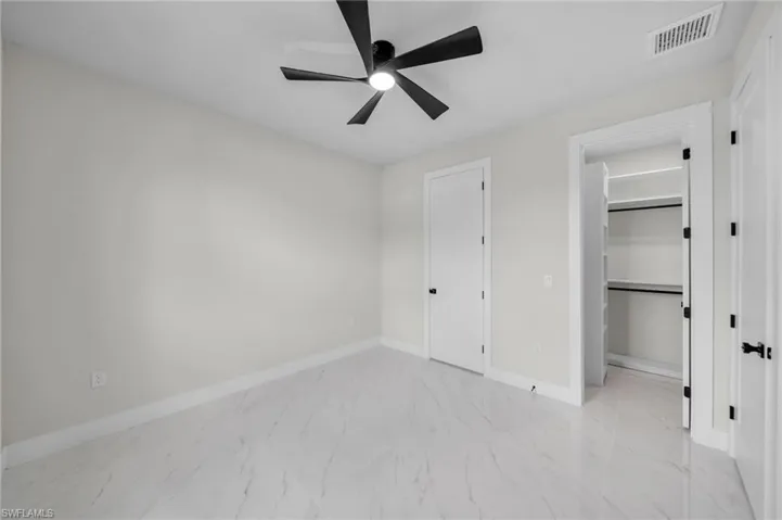 Unfurnished bedroom featuring baseboards, ceiling fan, marble finish floor, and visible vents