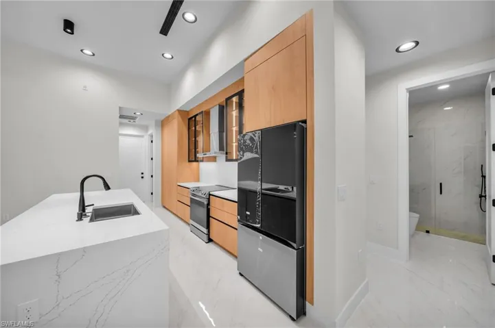 Kitchen with smart refrigerator, range with electric cooktop, a sink, and modern cabinets