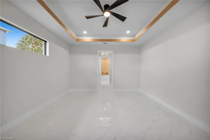 Spare room featuring recessed lighting, baseboards, a raised ceiling, and marble finish floor