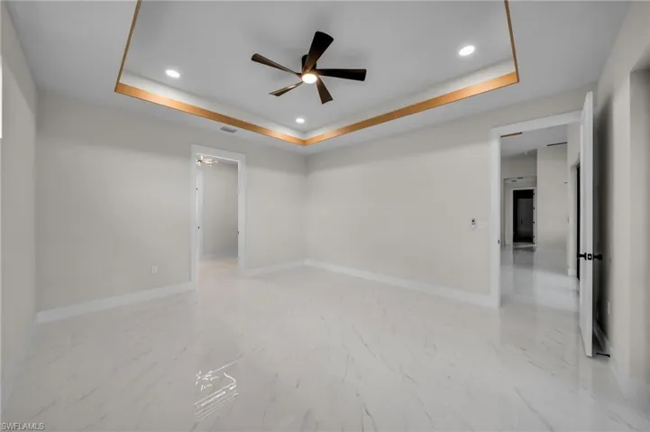 Unfurnished room featuring a ceiling fan, visible vents, baseboards, a tray ceiling, and recessed lighting