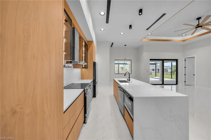 Kitchen with modern cabinets, a spacious island, a sink, stainless steel appliances, and recessed lighting