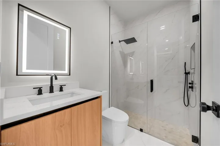 Bathroom with vanity, a marble finish shower, and toilet