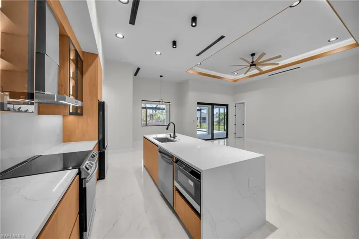 Kitchen with wall chimney range hood, appliances with stainless steel finishes, a sink, recessed lighting, and modern cabinets