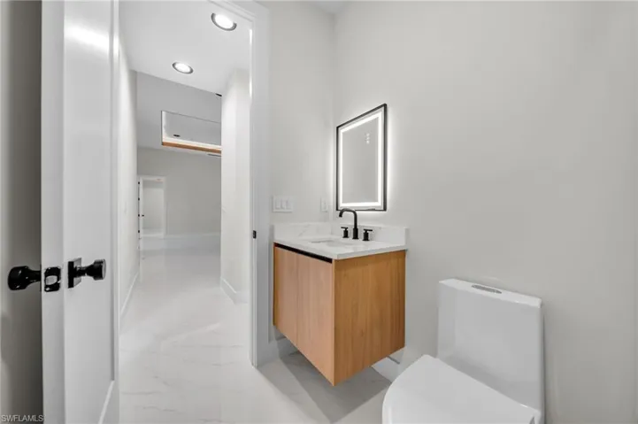 Bathroom with vanity, marble finish floor, toilet, baseboards, and recessed lighting