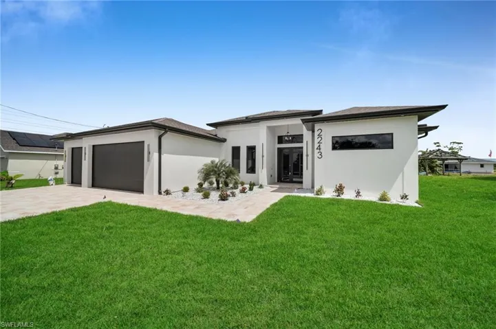 Prairie-style house with an attached garage, stucco siding, driveway, and a front yard