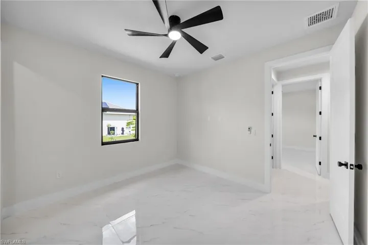 Empty room featuring ceiling fan, marble finish floor, and visible vents