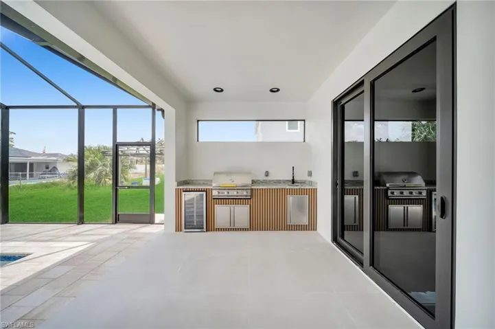 View of patio featuring glass enclosure, a sink, grilling area, and area for grilling